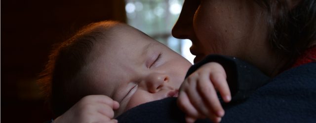 Enfant qui dort dans les bras de sa maman.